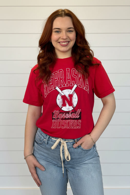 Person wearing a red 'Nebraska Baseball Huskers' t-shirt in a store setting