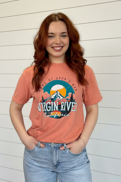 Woman wearing a 'Virgin River' t-shirt in a store with clothing and decor around her.